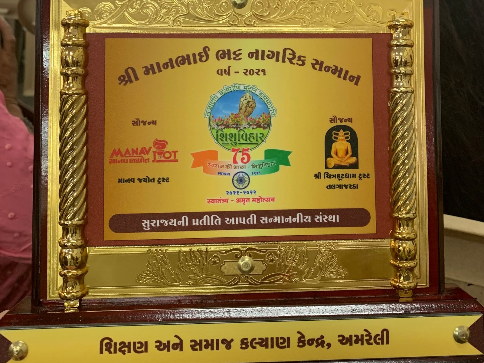 માનભાઈ ભટ્ટ નાગરિક સન્માનની તકતી — “વર્ષ ૨૦૨૧” અને નીચે “શિક્ષણ અને સમાજ કલ્યાણ કેન્દ્ર, અમરેલી” લખેલું છે