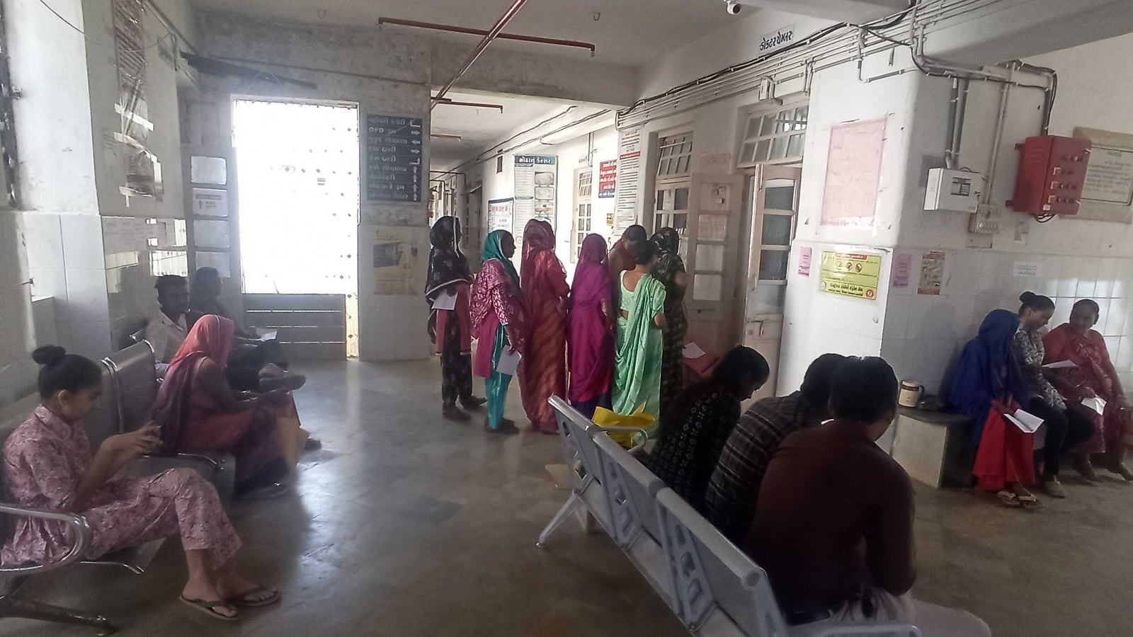 સામુદાયિક આરોગ્ય કેન્દ્રમાં તપાસ ખંડની બહાર બાંકડે બેઠેલી અને પરચી લઈને લાઇનમાં ઊભેલી મહિલાઓ
