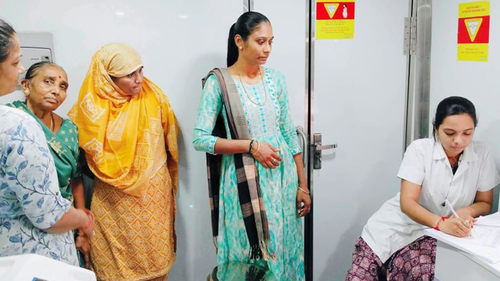 કેન્સર તપાસ કેમ્પના રજિસ્ટ્રેશન ટેબલ પર રાહ જોતી મહિલાઓ